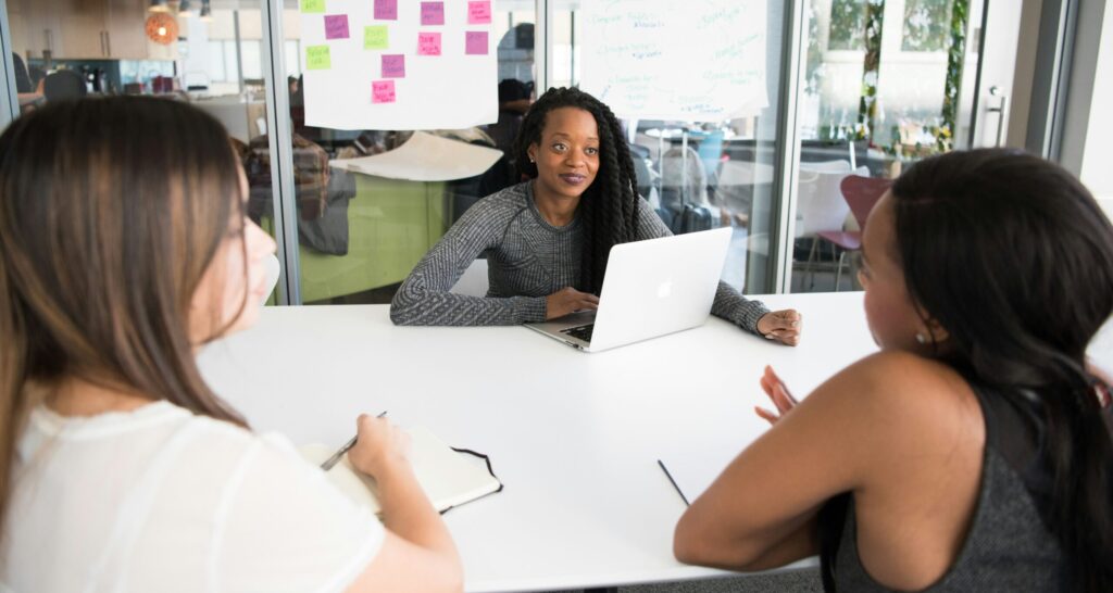 Three women sitting at a table looking at paperwork